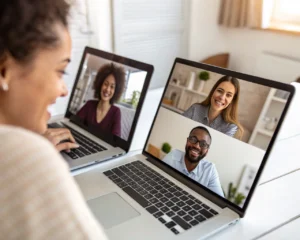 Equipo diverso trabajando en una reunión virtual en laptops, mostrando concentracion y colaboracion en un ambiente de oficina en casa.